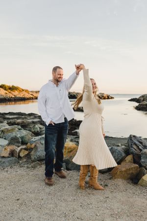 A couple dances together on a rocky beach at sunset. Engagement Session Newport, RI