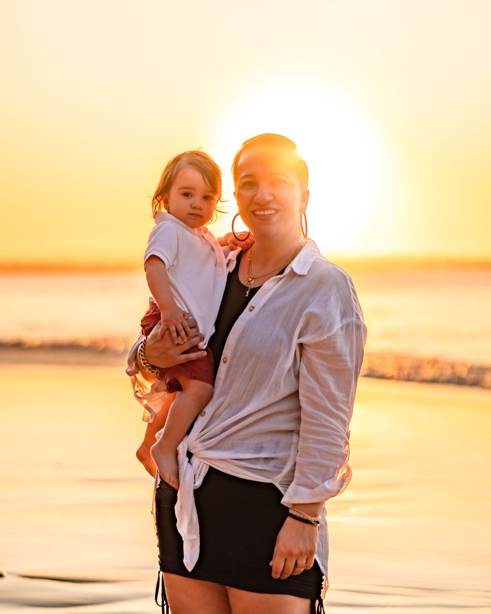 A Mother holding her young daughter being back lit by the sunset at Noosa. The sun sits perfectly behind there heads.