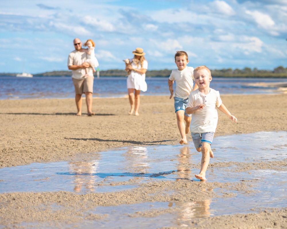 Beautiful family walking / running on the beach on a stunning summers day. Dad is holding his youngest daughter.