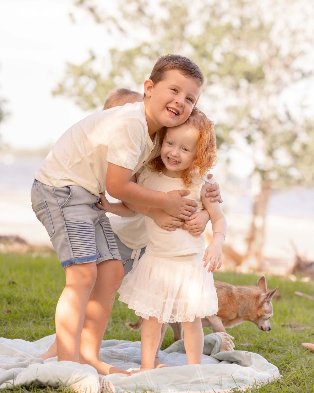 Two young kids, Brother and Sister cuddling each other with big beautiful smiles.