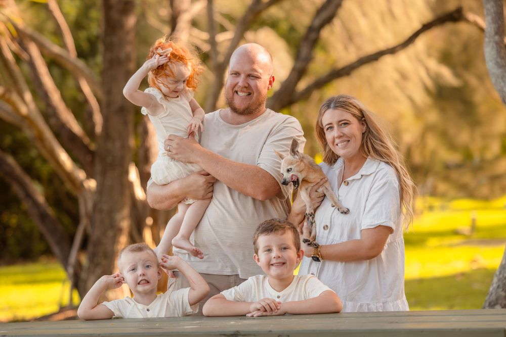 Family of 6, 2 parents, 3 kids and there old dog. Located in a park lit by the rich, warm afternoon sun.
