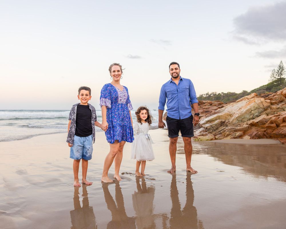 Family of Four, Mum, Dad, Daughter and son, holding hands together as they pose for there Family photos on the Beach.