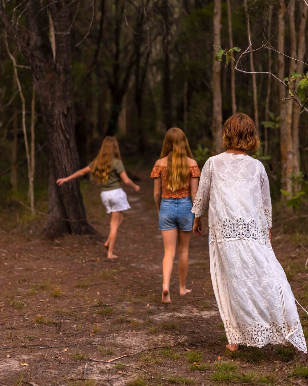 Mother and two daughters strolling into a woodland, forest seen