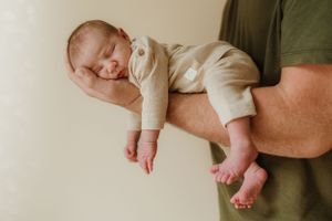 Tiny baby feet being gently held in adult hands.