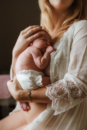 Delicate moments with a newborn baby wearing lace in warm indoor lighting.