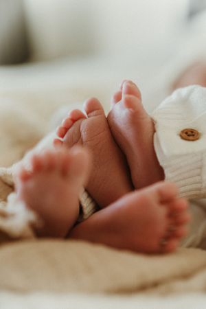 Close-up view of tiny newborn baby feet wrapped in soft white fabric.