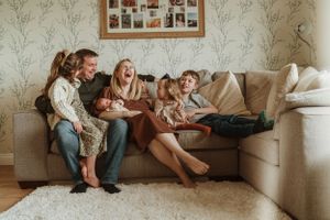 Lifestyle family photography session showing playful moments on a living room couch.
