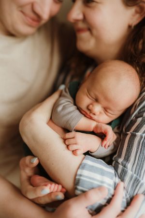 An intimate family moment with a sleeping infant nestled between parents.