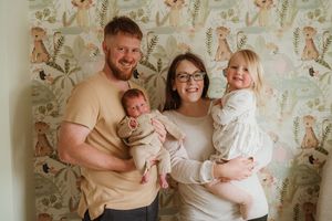Indoor family portrait session with floral wallpaper background.