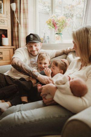 A family shares cozy moments together on a comfortable couch by a bright window.