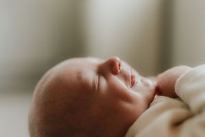 Close-up profile view of a sleeping newborn baby with soft natural lighting.