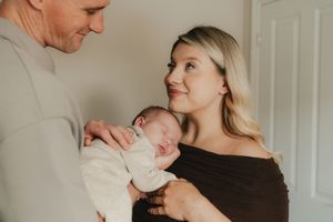 A series of tender moments between parents and their newborn baby in a bright, white room.