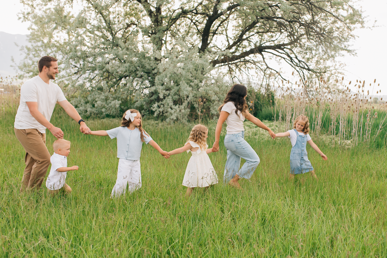 A family shares a tender moment outdoors during golden hour with trees in the background.