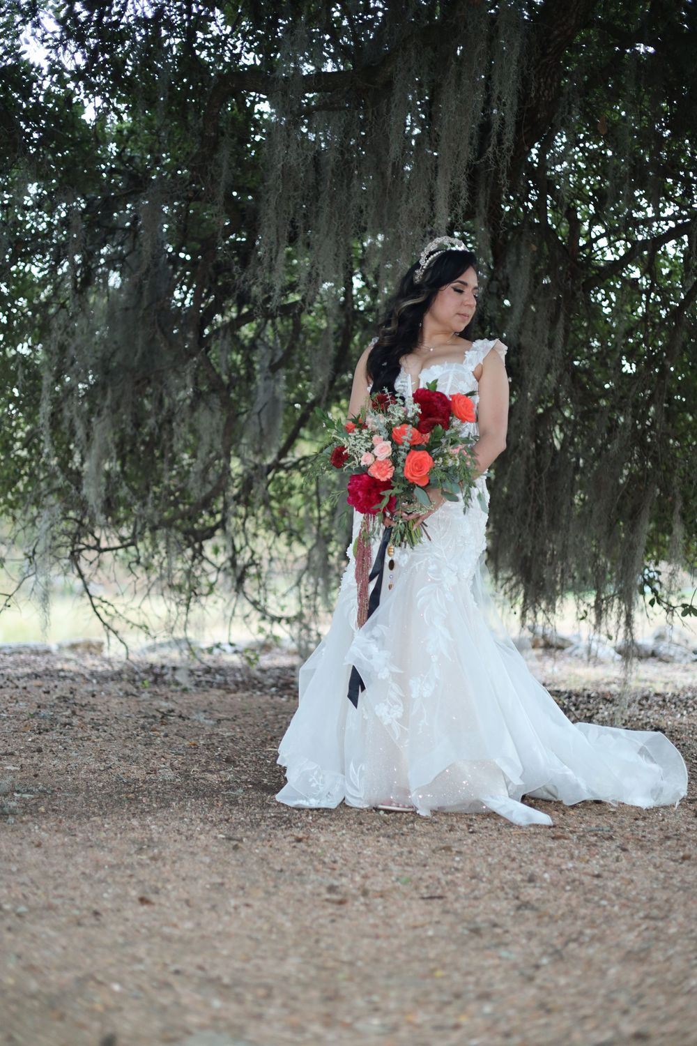 A series of romantic bridal portraits featuring a white wedding dress and red floral accents under Spanish moss in a garden setting.