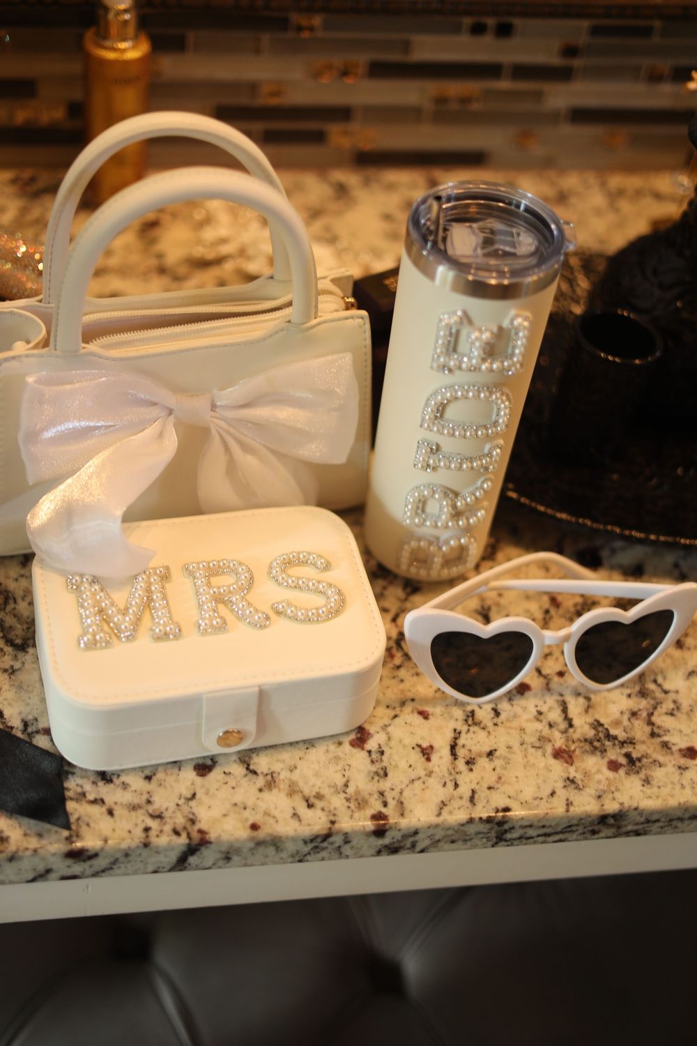 Collection of white bow accessories with 'Mrs' text and vintage-style embellishments on granite counter.