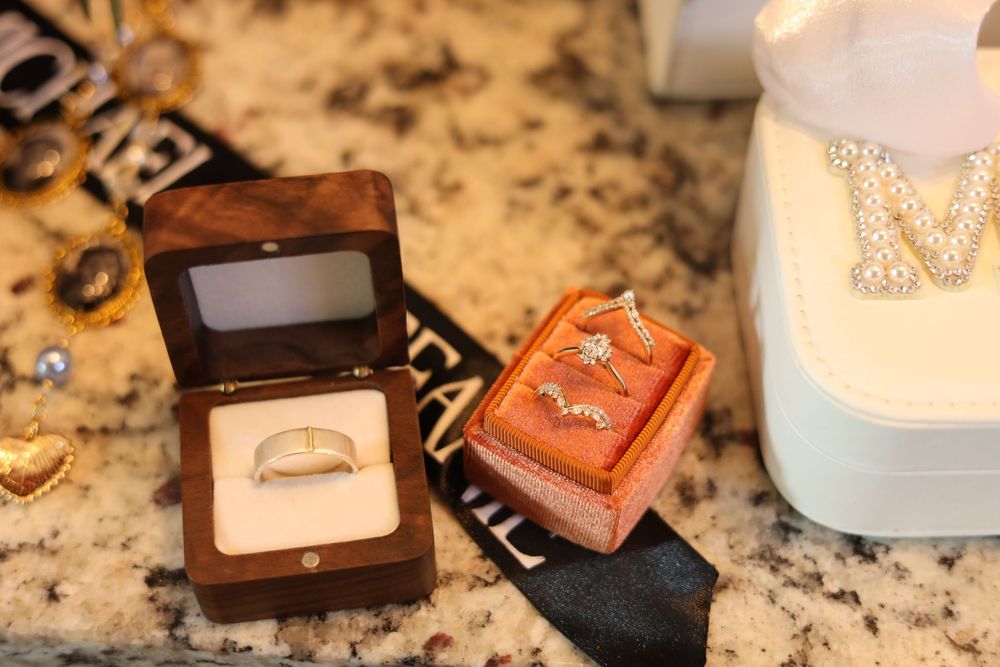 Wedding jewelry and accessories displayed on a granite countertop including rings, necklaces, and decorative boxes.