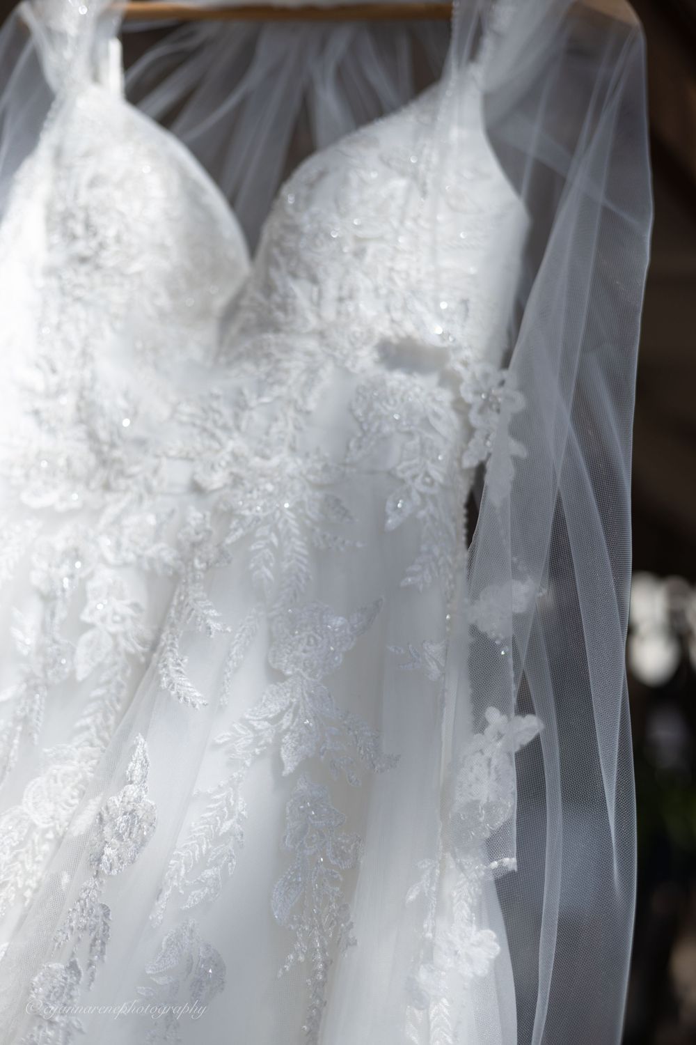 Delicate white lace and beading detail on wedding dress bodice with sheer veil overlay.