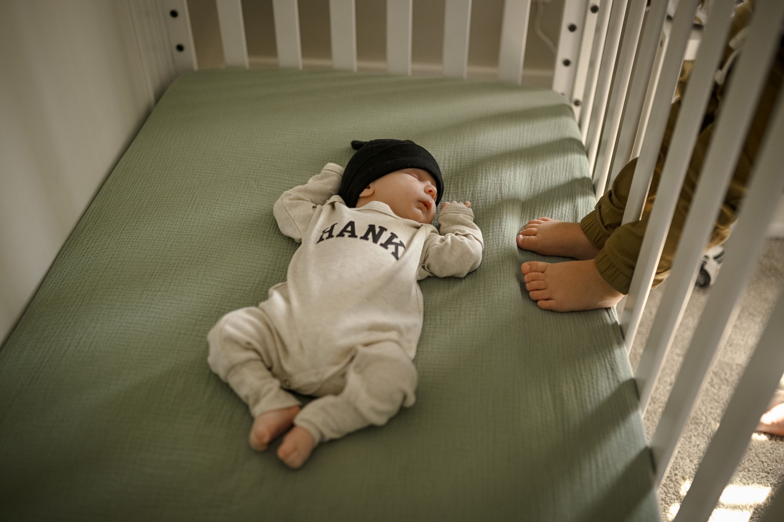 A baby wearing a Giants onesie lies on a green couch cushion.