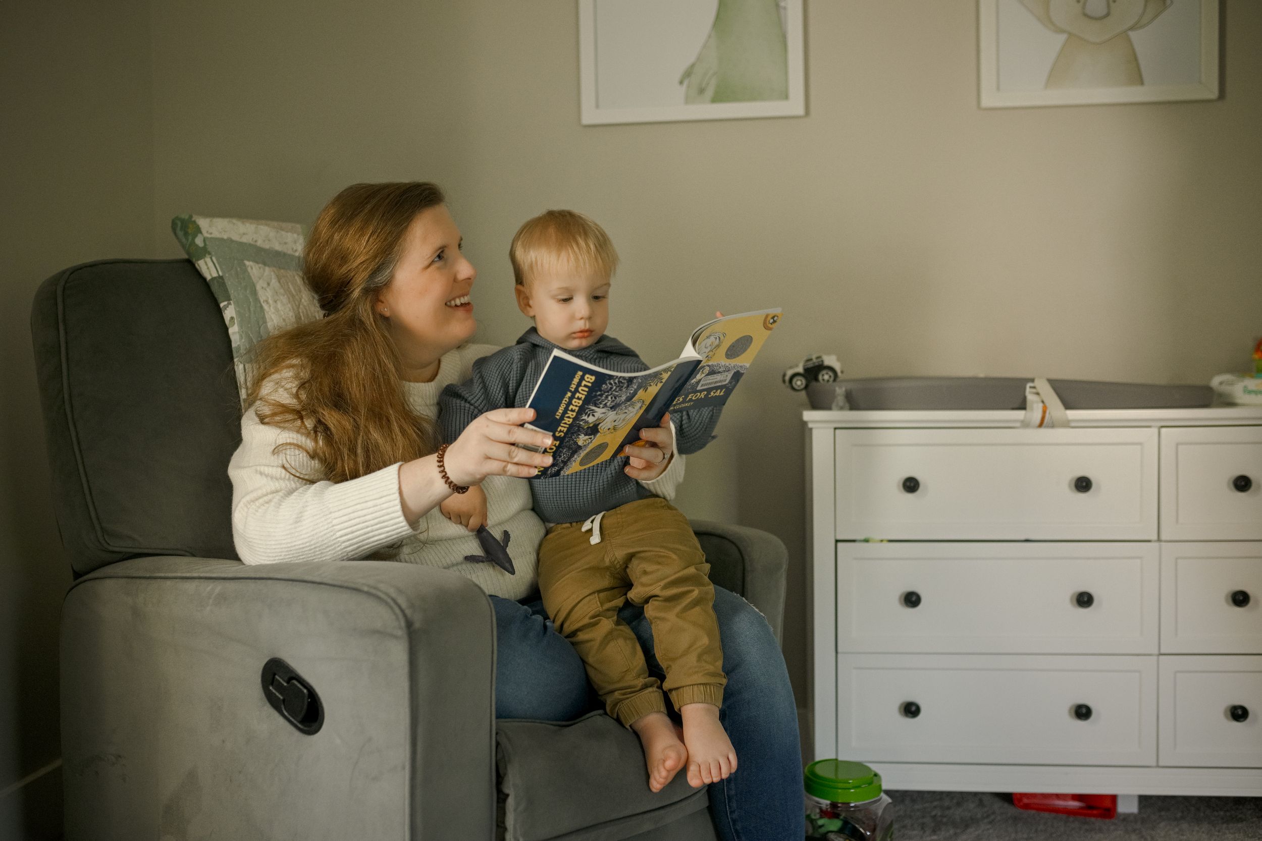 A cozy reading session on a white bed with toys and books.