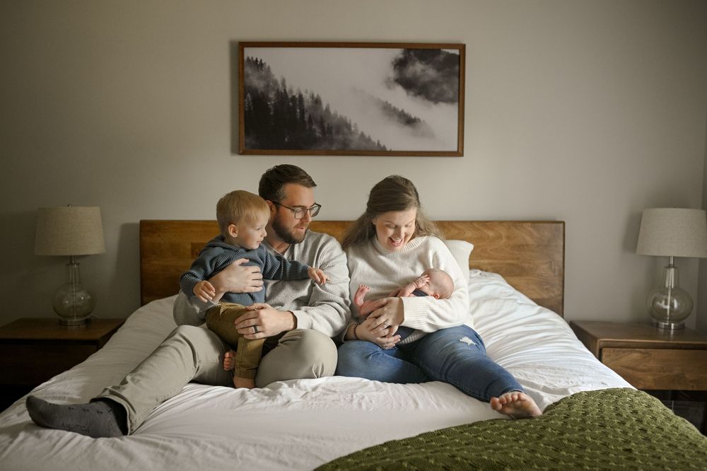 Intimate family moment reading together on a bed with natural lighting.