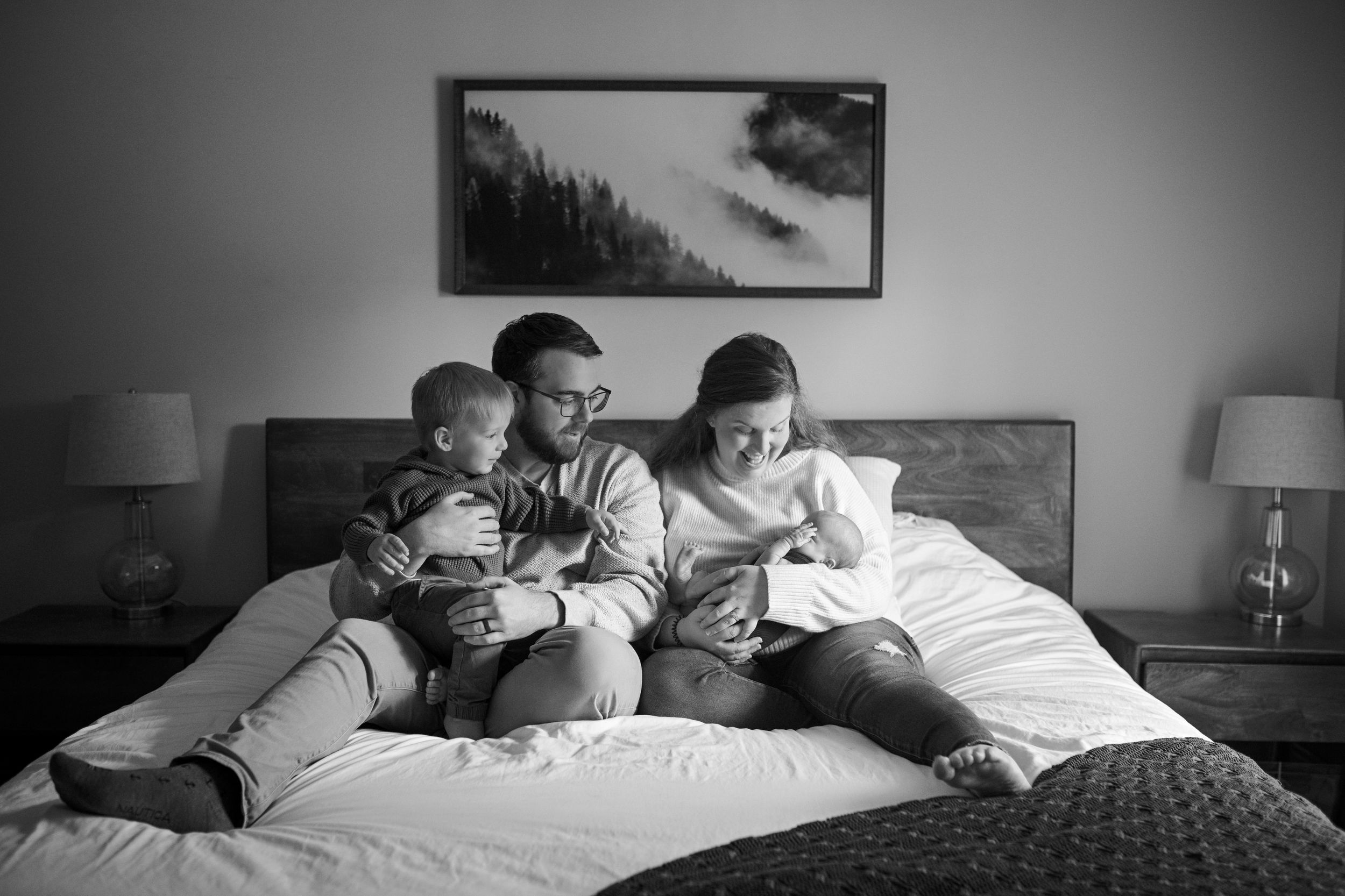 Family relaxing together on a bed while reading books.