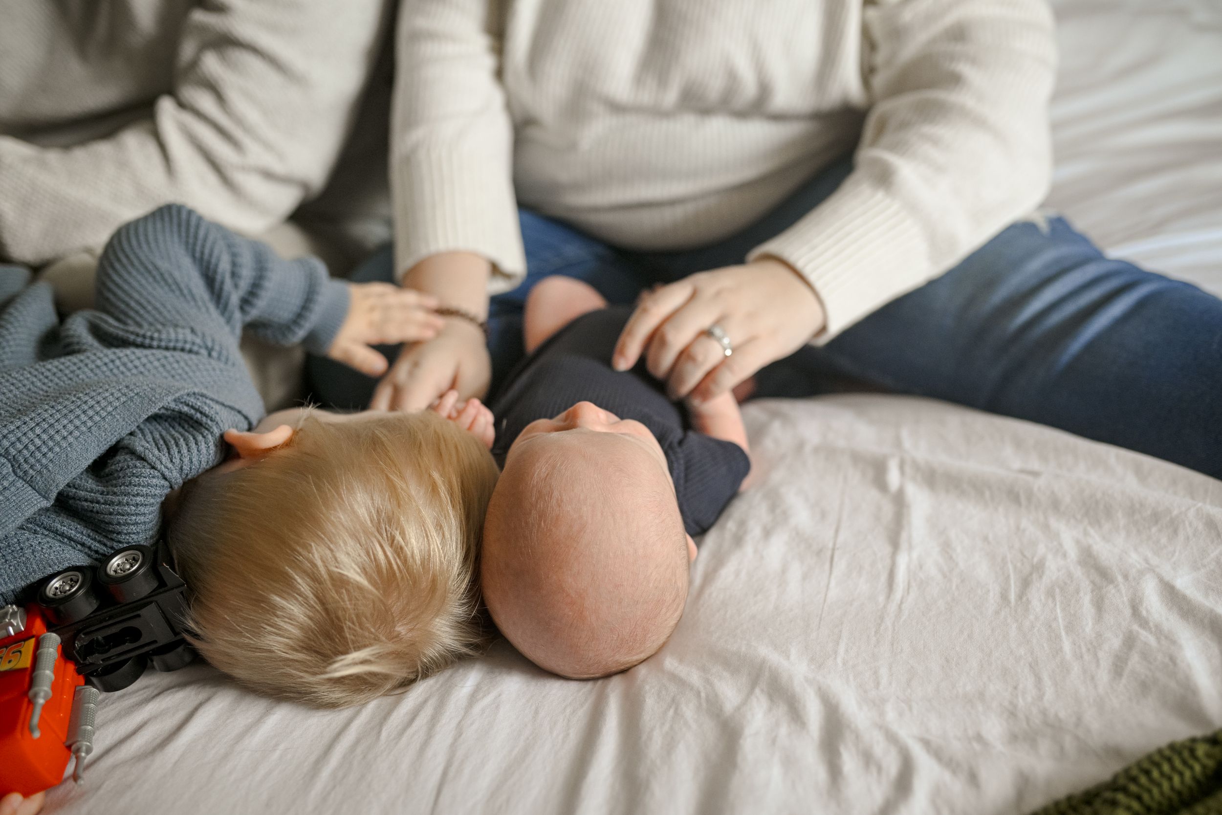 Close-up view of family members lying together on white bedding.