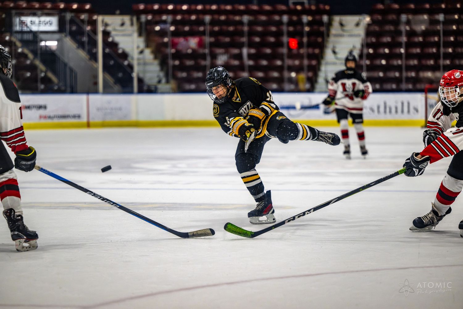 Action shot of a male hockey player taking a shot between two defenders.