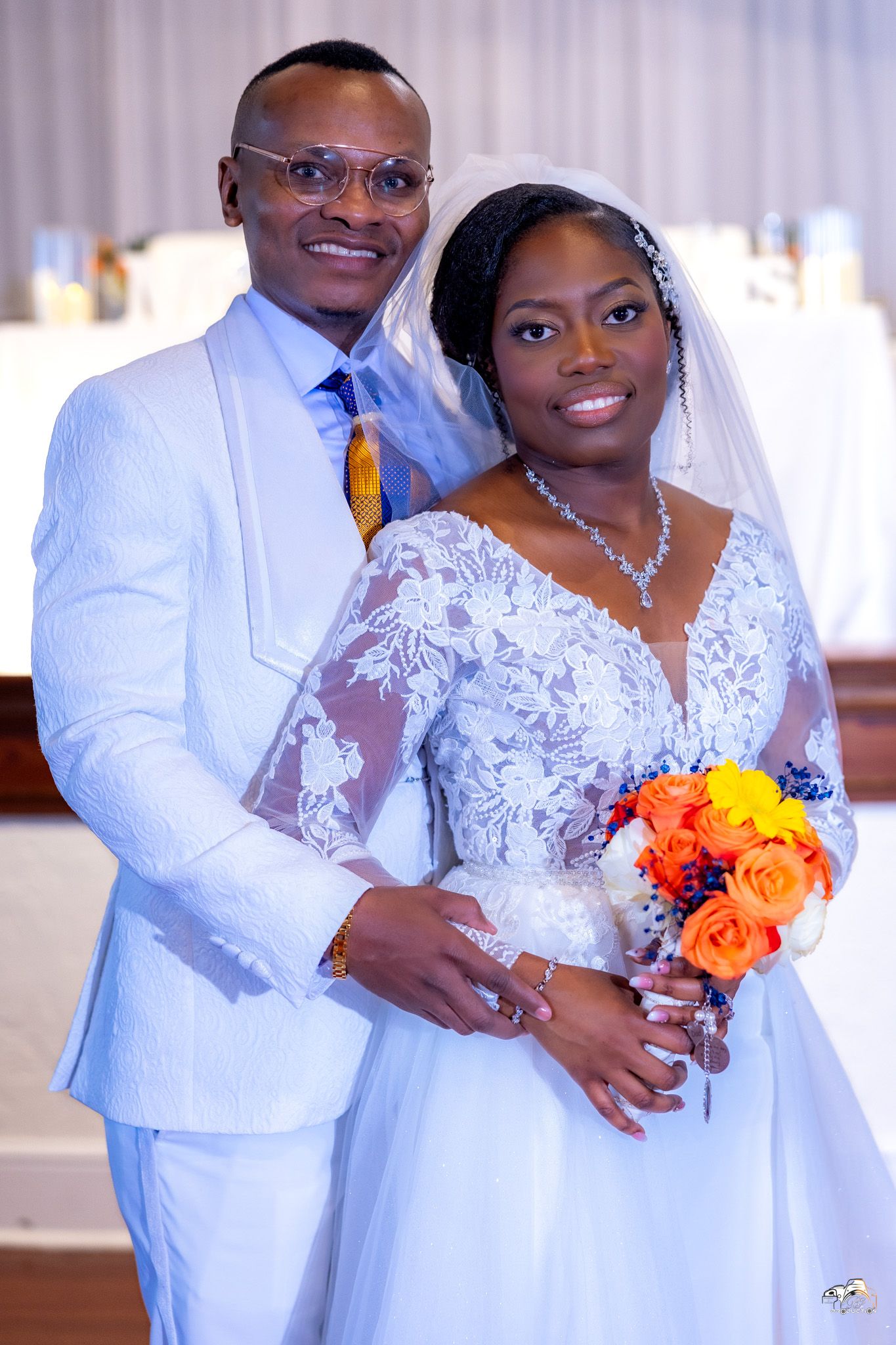 Wedding portrait showcasing couple in white attire with colorful bouquet in traditional church setting.