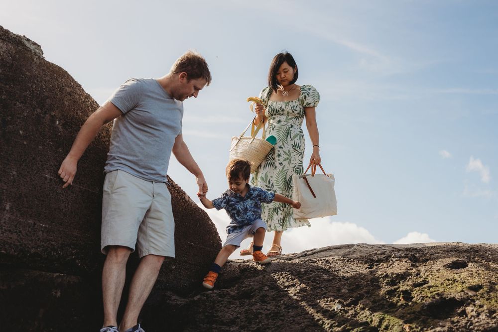 A couple explores a rocky coastal landscape during sunset, walking along rugged cliffs near the ocean.