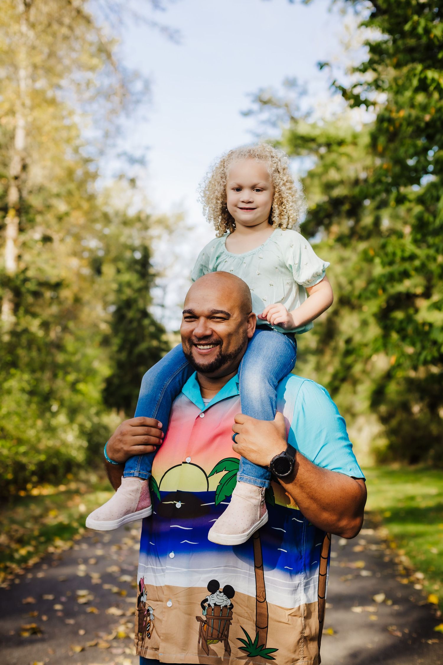 A playful moment captured on a nature path as a parent gives a shoulder ride on a sunny autumn day.