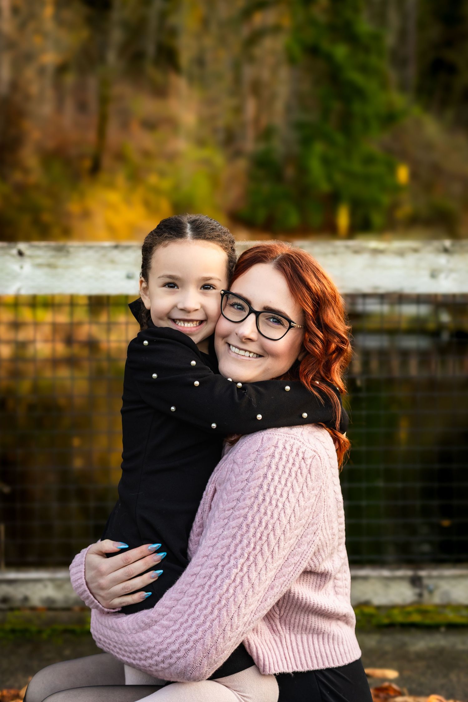 Two people share a warm embrace while wearing cozy winter sweaters outdoors on an autumn day.