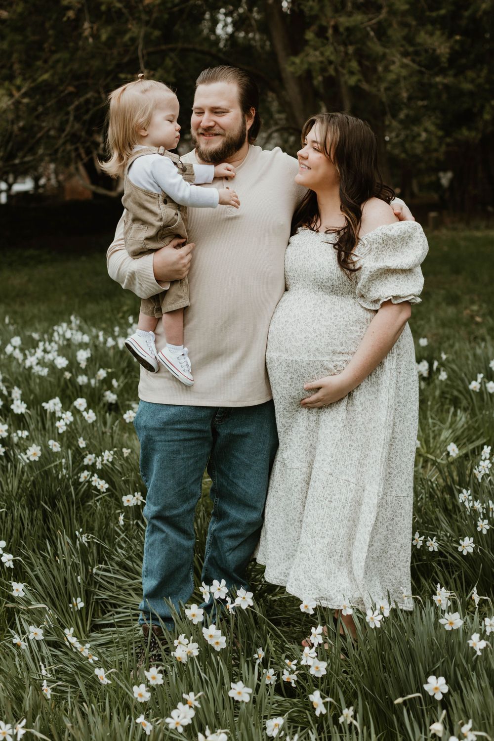 Family portrait in a spring garden with blooming white daffodils.