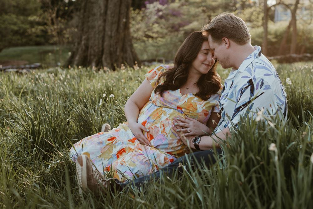 Couple lying in a spring meadow surrounded by wildflowers during sunset.
