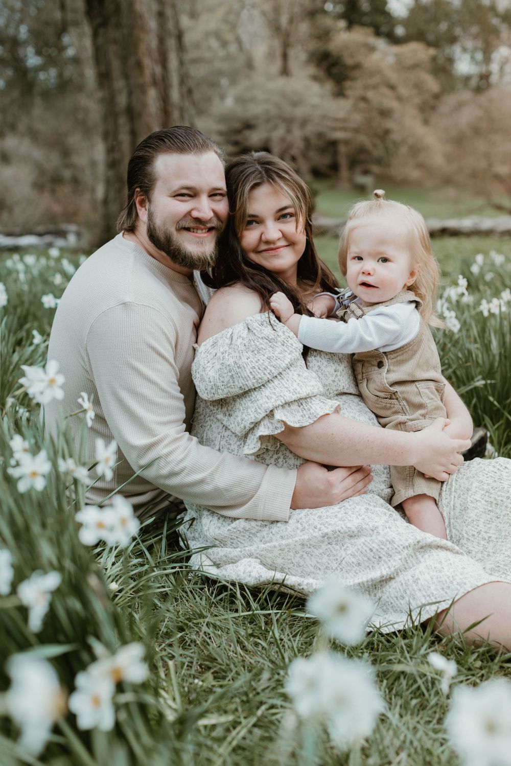 Family sitting together among blooming spring daffodils during an outdoor photo session.