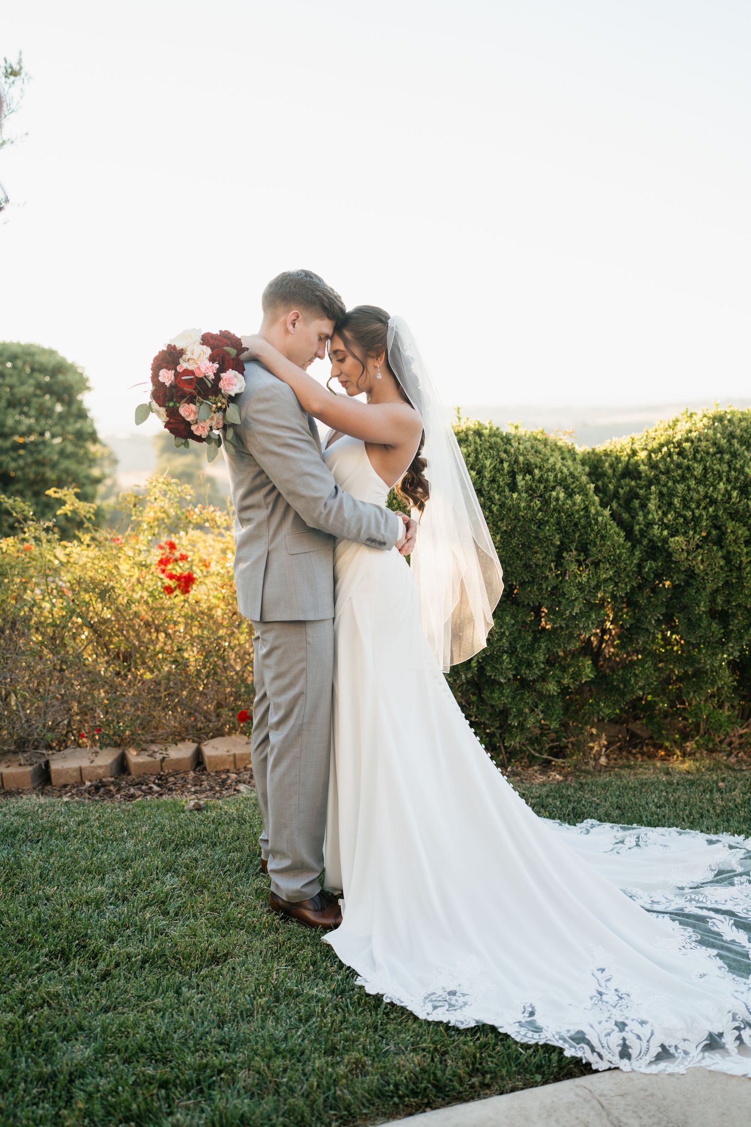 Romantic moment shared between a couple in wedding attire against a garden background with lush greenery.