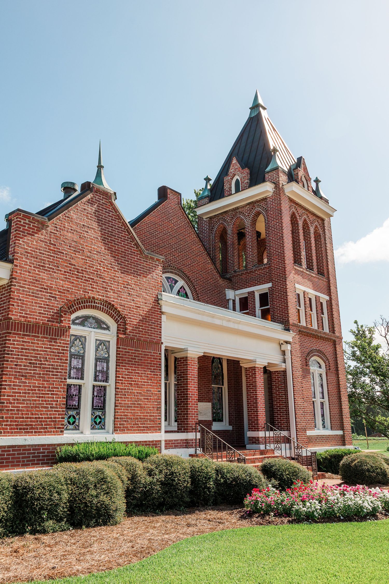 Historic red brick church with Gothic architecture and manicured landscaping.