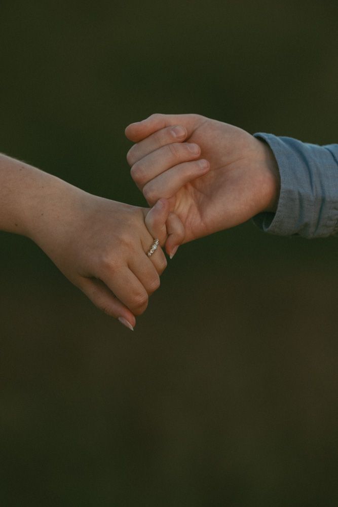 two hands in the middle of the frame, interlocking fingers to show off brides engagement ring.
