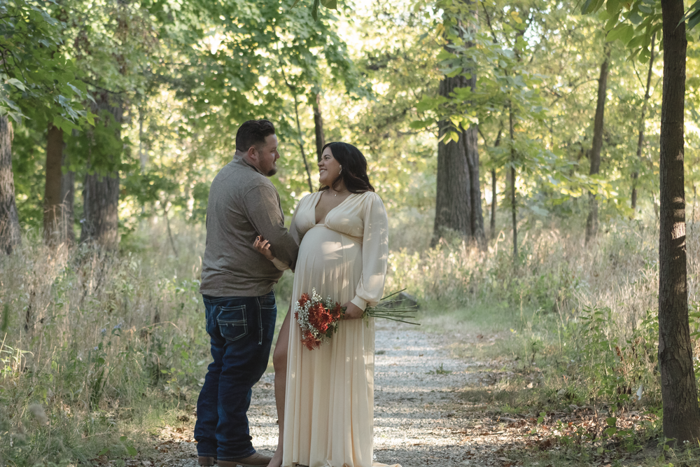 A couple poses for romantic photos on a serene forest path during golden hour.