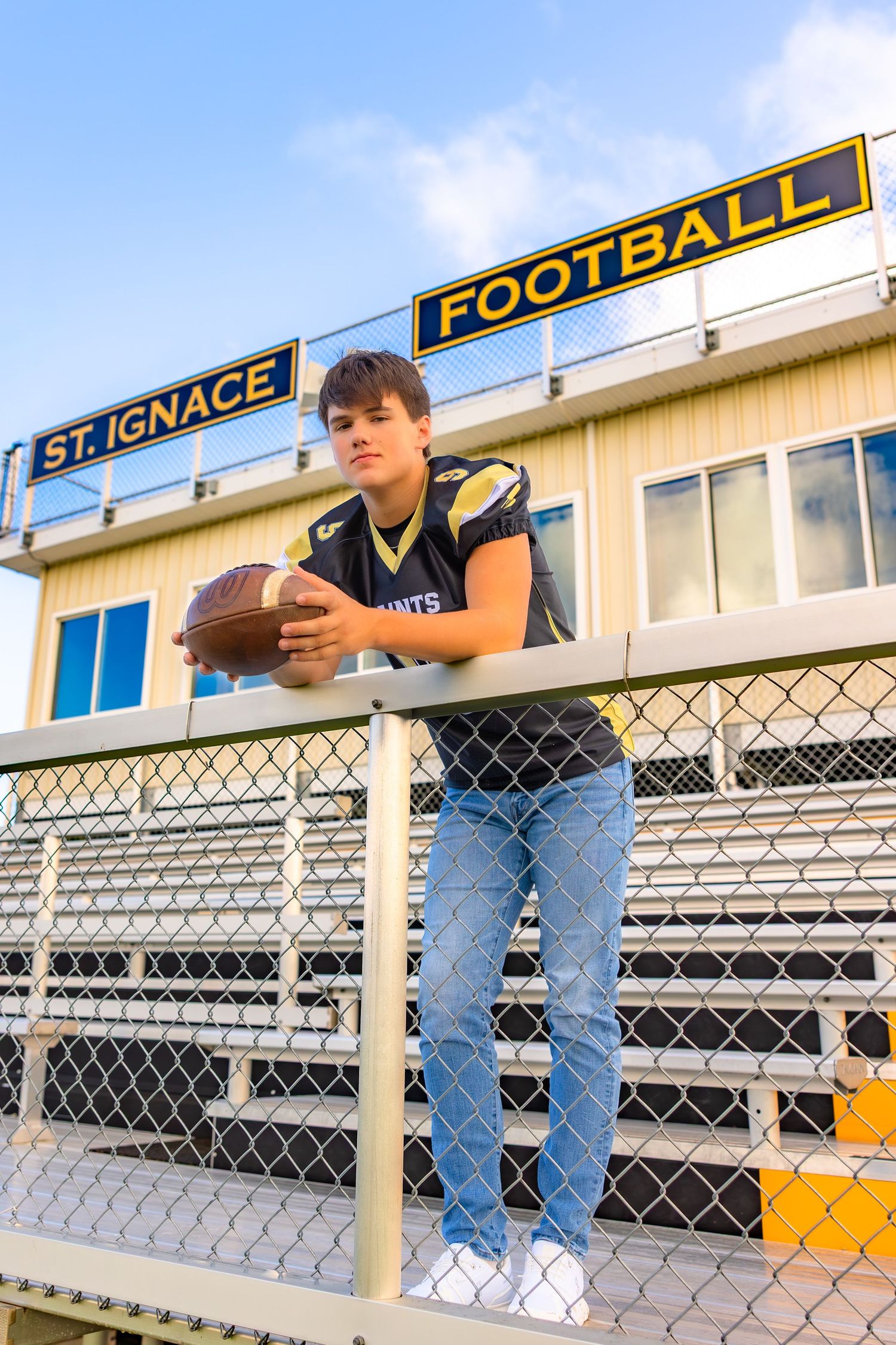 A football stadium bleacher section with yellow and blue signage on a sunny day. Katharine Rose Photography | Saint Ignace