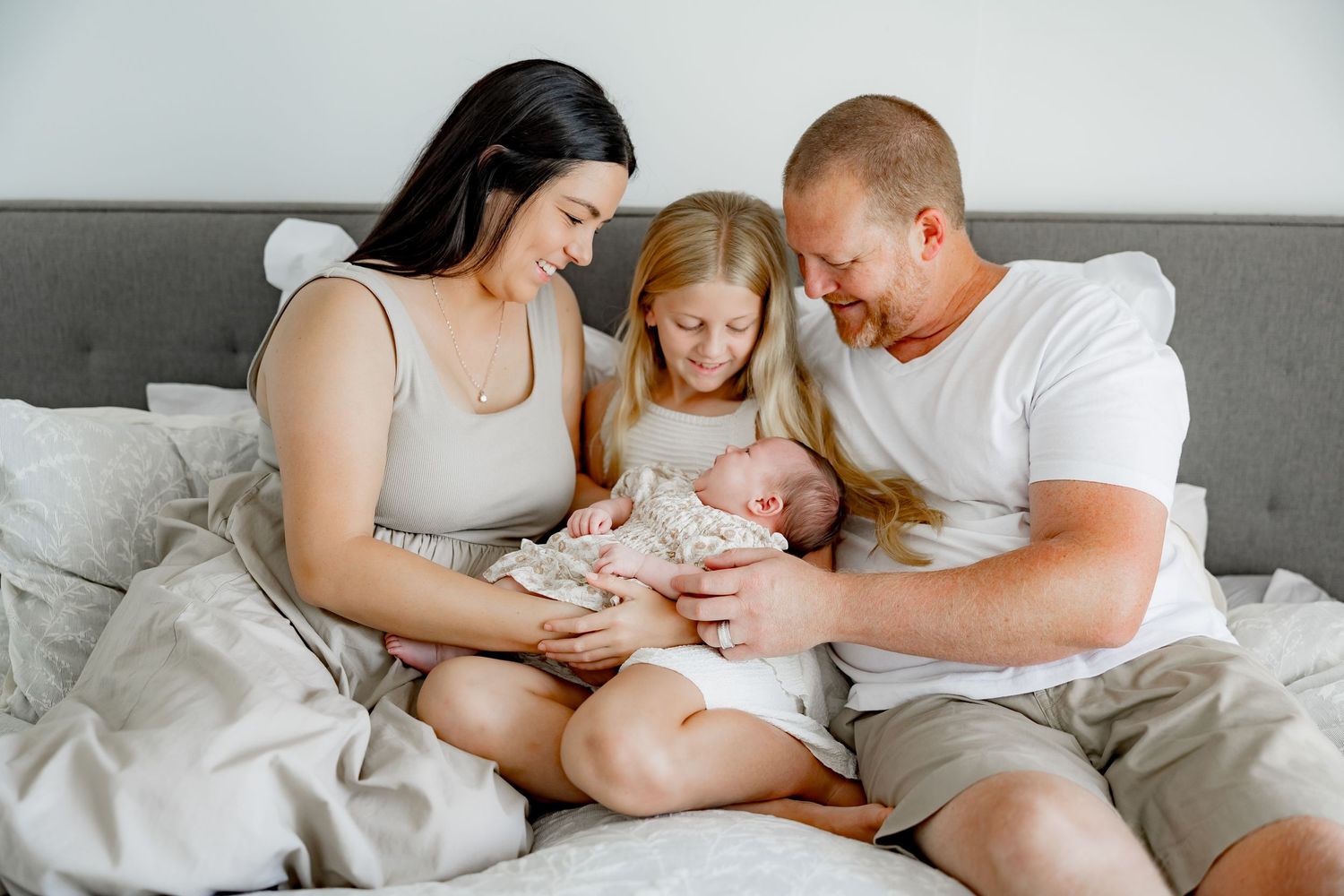 A tender family moment in a bedroom as they gather on a bed with a small child.