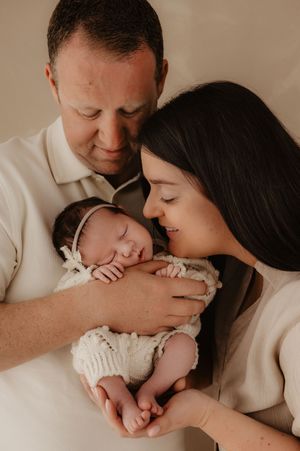 Intimate family portrait of sleeping newborn being cradled lovingly.