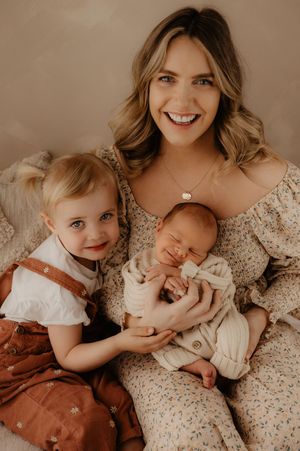 Sweet family moment captured in warm studio lighting with floral dress and earth tones.