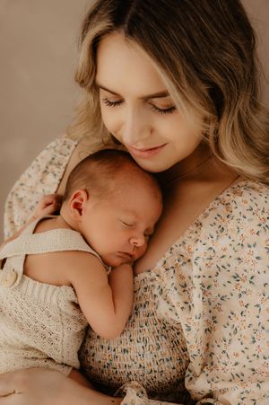 Intimate portrait of a mother holding her sleeping newborn baby against her chest.