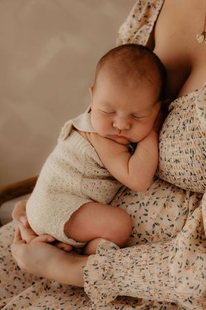Sleeping infant cuddled against floral patterned fabric in warm tones.