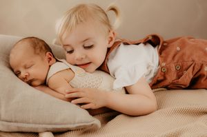 Two young siblings share a tender moment as they cuddle on a couch together.