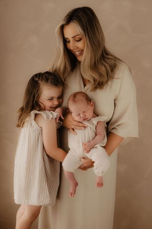Tender family moments in soft beige tones showing affectionate poses with newborn.