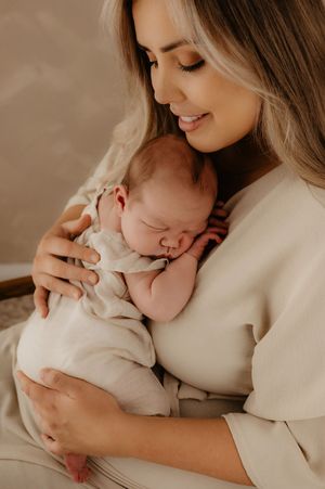 Gentle motherhood portraits in warm tones showing tender moments with sleeping infant.