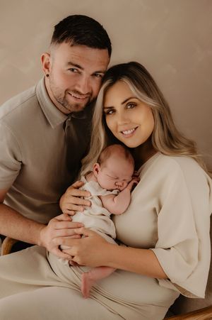 Intimate family portrait session in neutral tones showing tender moments with newborn.