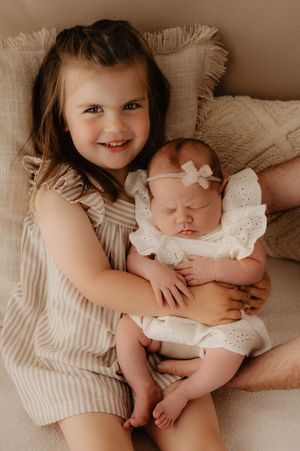 Sweet sibling portraits in vintage tones showing tender moments with newborn baby.