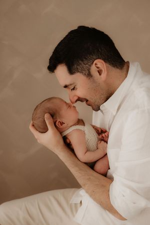 Intimate portrait of a parent sharing a gentle moment with their sleeping newborn in soft lighting.